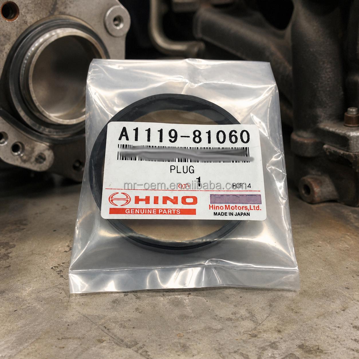 A close-up shot of a circular engine plug sealed in a clear plastic bag, featuring a white Hino Genuine Parts label with the part number A1119-81060.